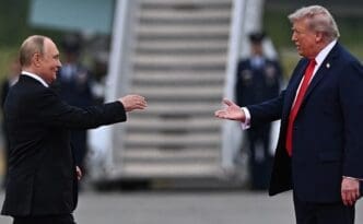 U.S. President Trump and Russian President Putin greet each other with extended hands on an airport tarmac in Anchorage, Alaska.