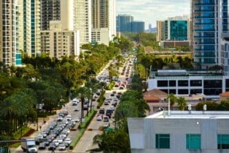 An aerial view of a busy street with congested traffic in Sunny Isles Beach, Florida, with a dense skyline of high-rise condos and hotels.