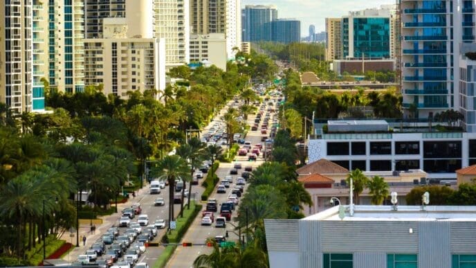 An aerial view of a busy street with congested traffic in Sunny Isles Beach, Florida, with a dense skyline of high-rise condos and hotels.