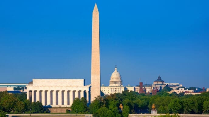 The National Mall in Washington, D.C., with the Washington Monument, Lincoln Memorial, and U.S. Capitol Building under a clear blue sky.