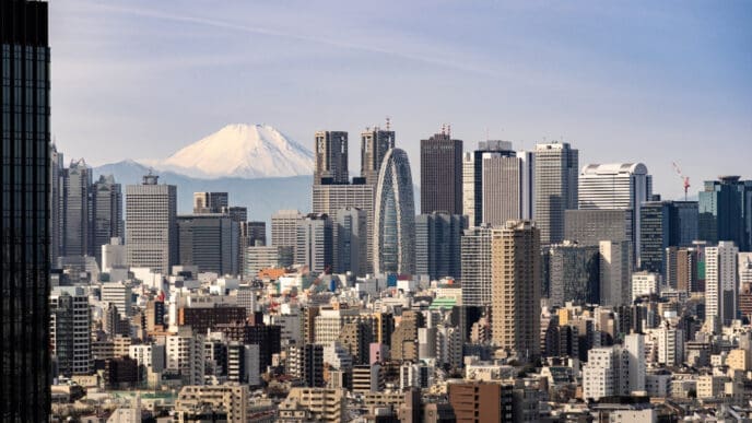 The skyline of Tokyo is seen with numerous financial buildings and the snow-capped Mount Fuji in the background.