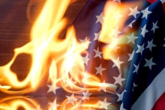 A photograph of the American flag, with its stars and stripes, is engulfed in bright orange and yellow flames.