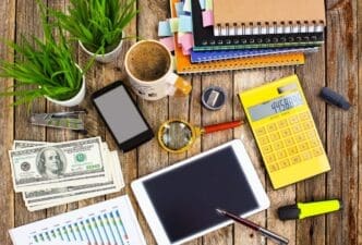 A desk holds office supplies like a laptop, pens, and a notebook.