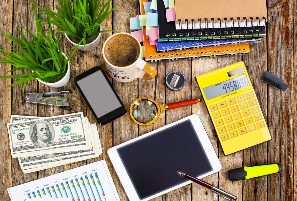 A desk holds office supplies like a laptop, pens, and a notebook.
