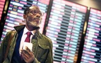 A Black businessman in a suit looks at his wristwatch, possibly indicating he is waiting or concerned about the time.