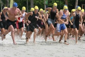 Athletes run along a sandy beach.