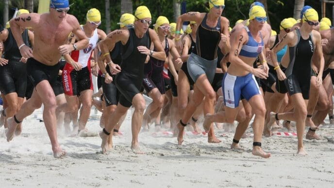 Athletes run along a sandy beach.