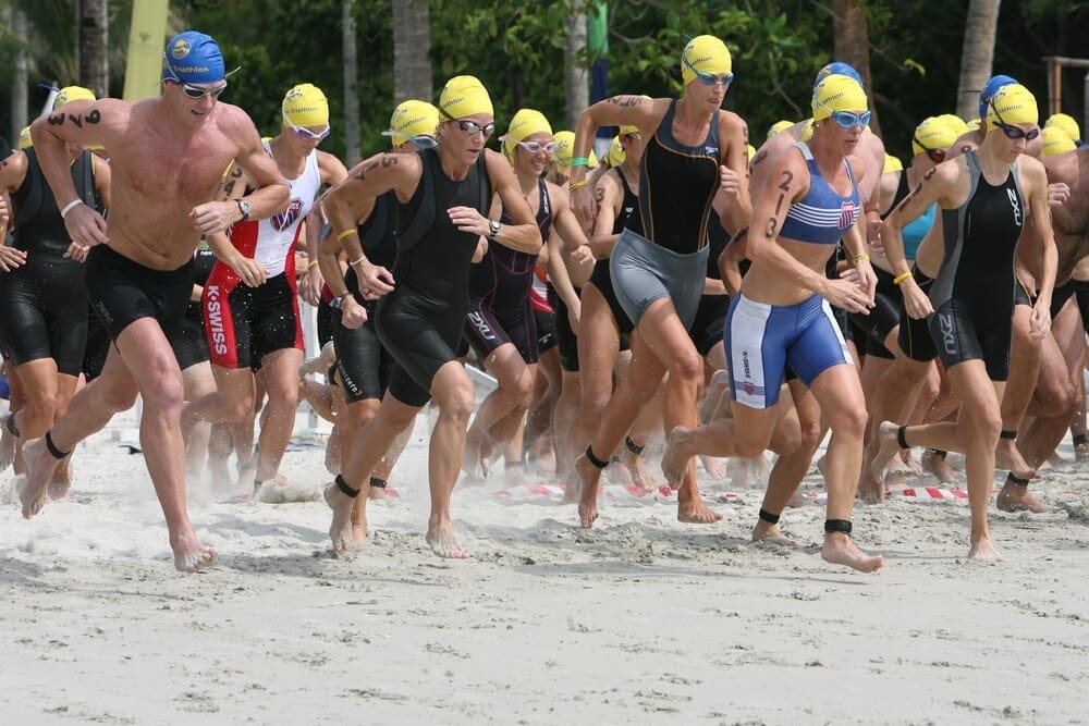Athletes run along a sandy beach.