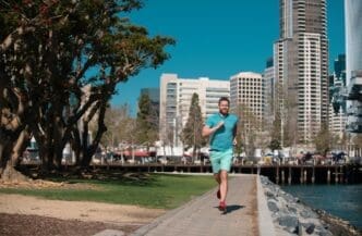 A young man runs through a city on a sunny day.