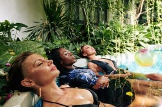 Two women in swimwear relax in an outdoor swimming pool.