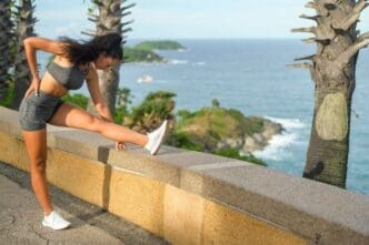 A fit woman in sportswear exercises on a seaside mountain peak.