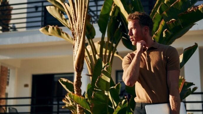 Young man standing outdoors in sunlight, enjoying a vacation in nature.