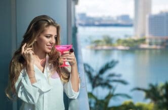Blonde woman enjoys a cocktail on a terrace balcony during summer vacation.
