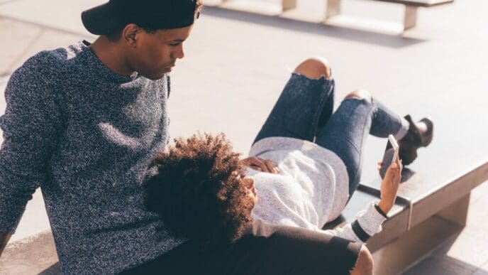 A young Black couple smiles as they take a selfie.