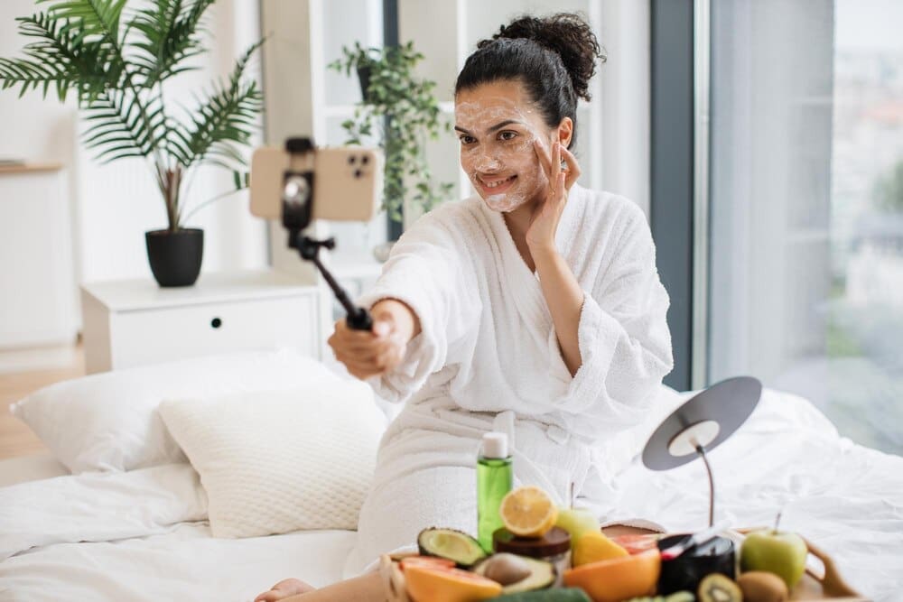 A person wearing a facial mask holds a smartphone camera, likely taking a photo or video.