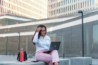 A businesswoman works on a laptop while seated outside.