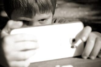 Close-up of a young boy holding a mobile phone.