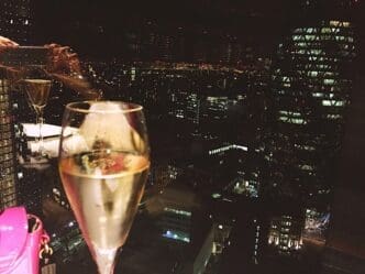 Close-up of a champagne flute reflecting the lights of buildings at night.