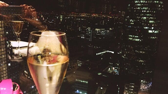 Close-up of a champagne flute reflecting the lights of buildings at night.