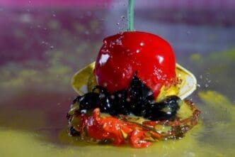 Close-up of a glistening red strawberry with water droplets on a wooden table.