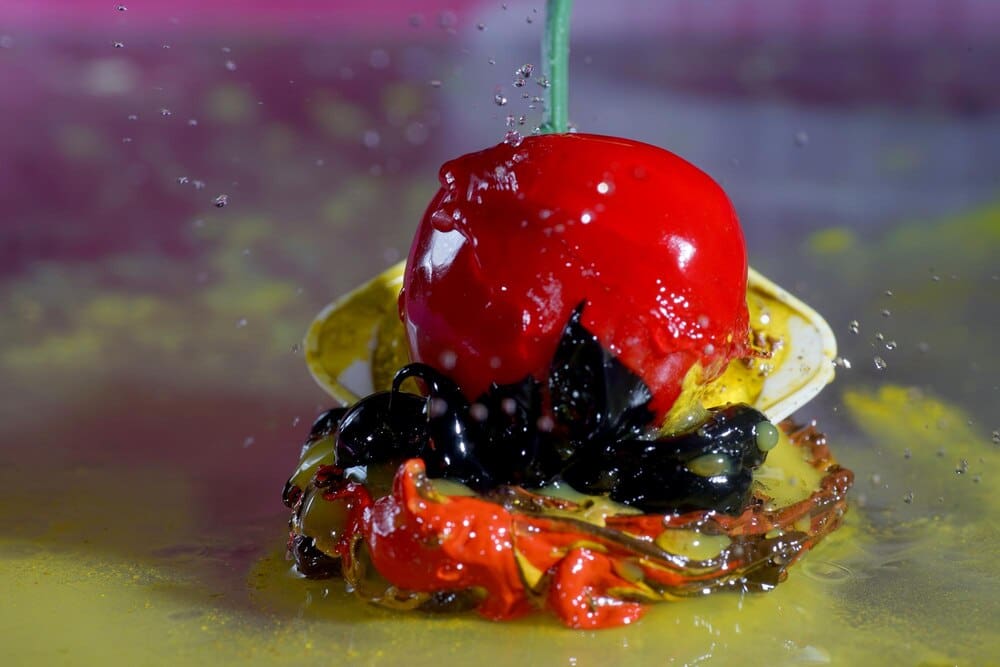 Close-up of a glistening red strawberry with water droplets on a wooden table.
