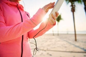 Woman's hands hold a mobile phone up against a bright sky.