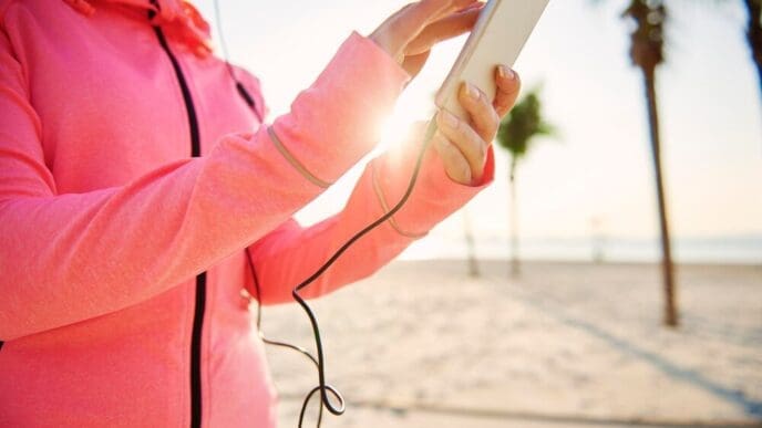 Woman's hands hold a mobile phone up against a bright sky.