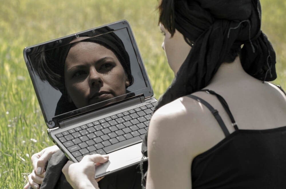 A woman is shown in a close-up view, focused on using a laptop.