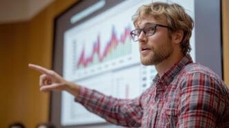 A presenter points to a chart on a screen while explaining complex data during a presentation.