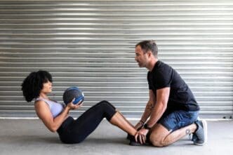 A couple works out together, using a medicine ball to perform an exercise.