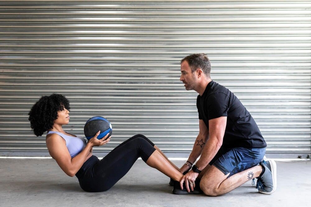 A couple works out together, using a medicine ball to perform an exercise.