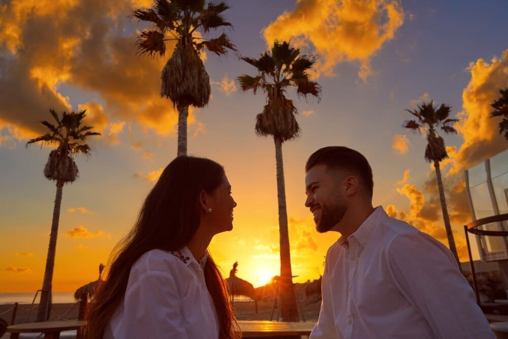A young couple embraces on a beach at sunrise.