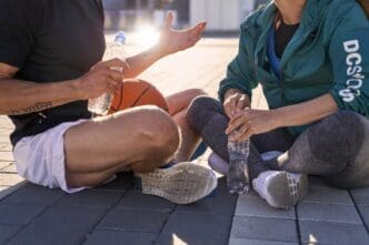 A cropped photo shows a couple in sportswear, resting and drinking water after a basketball workout.