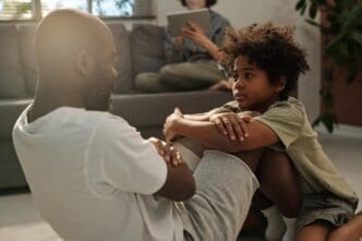 A young boy watches his father as he does sit-ups.