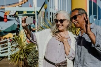 A smiling senior couple takes a selfie together at an amusement park.