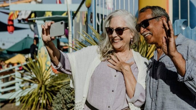 A smiling senior couple takes a selfie together at an amusement park.
