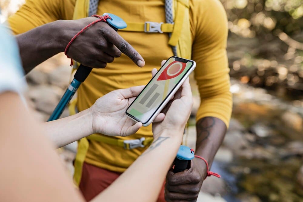 A couple uses a cell phone with a satellite map to navigate while trekking up a mountain.