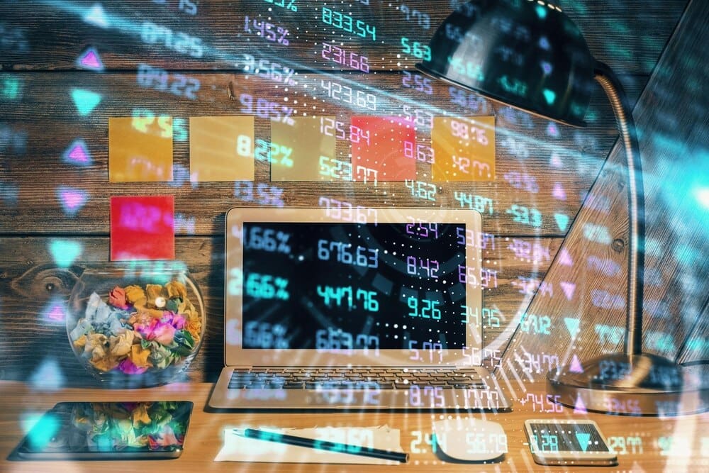 Double exposure shows a forex graph overlaid on a workspace with a computer, representing international online trading.