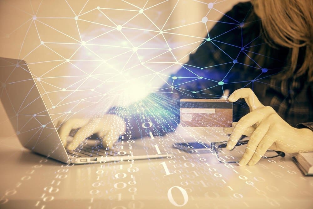 Double exposure shows a woman holding a credit card superimposed with a data-themed hologram related to online shopping.