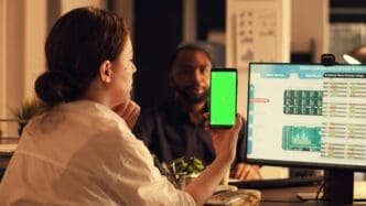 Person holding a smartphone with a greenscreen template, analyzing a stock market trend on a chroma key background.