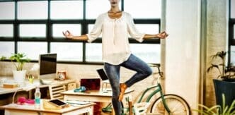 A woman in business attire stretches on a yoga mat.