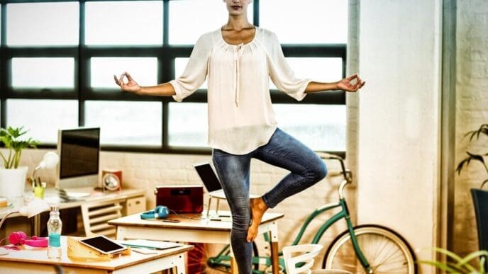 A woman in business attire stretches on a yoga mat.