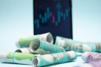 Smartphone displaying a stock chart and rolled currency, symbolizing financial growth.