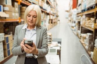 Warehouse manager in a warehouse, using a handheld device while looking intently at the screen.