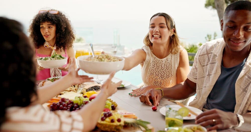 People of diverse backgrounds enjoy a festive outdoor lunch party in a backyard, celebrating a public holiday.