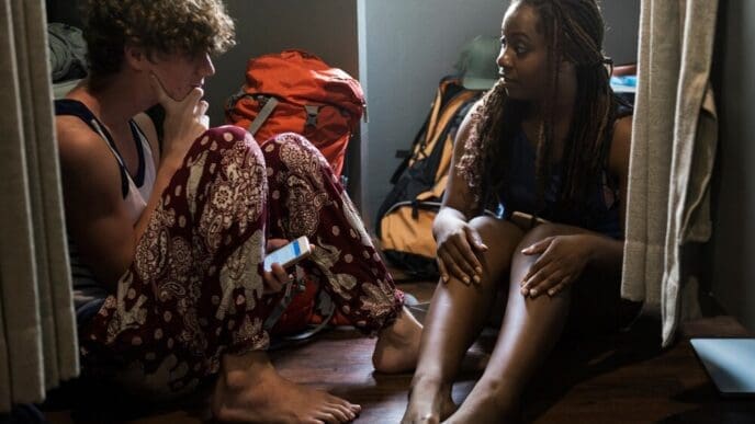 Two friends sit on a wooden floor, engaged in conversation.