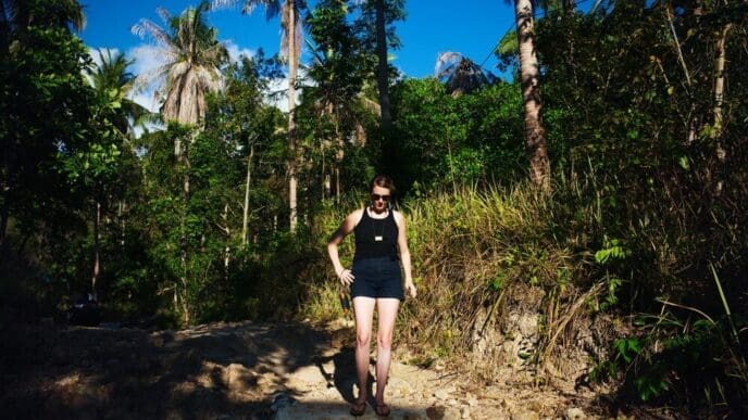 Young woman stands in front of trees.