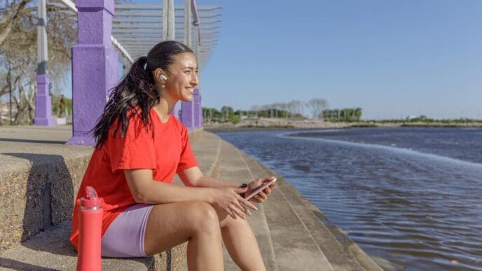 A young woman in athletic wear rests on a set of stairs, taking a break.