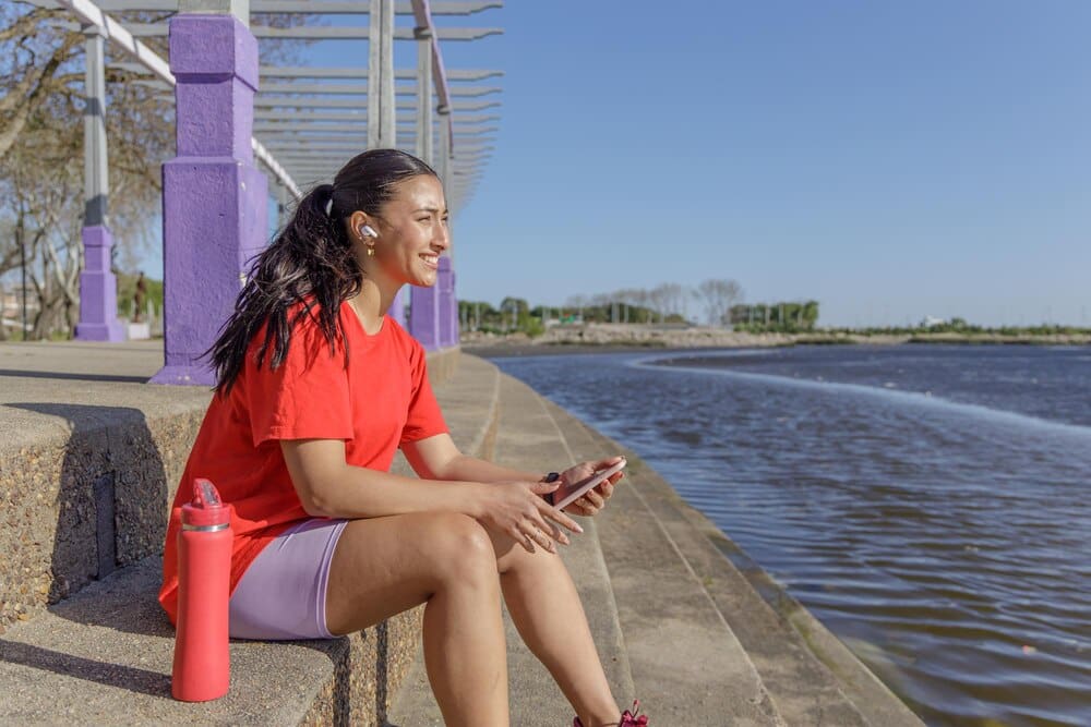 A young woman in athletic wear rests on a set of stairs, taking a break.