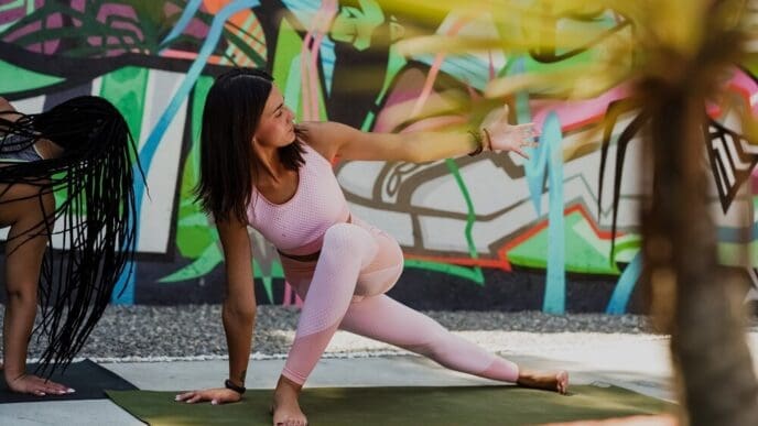 A group of people, including a yoga teacher, are doing yoga poses outdoors.